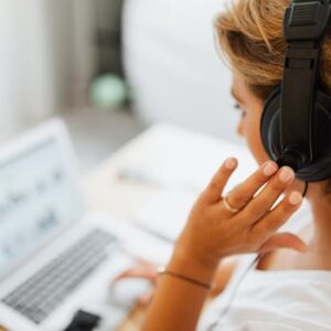 Woman at home using headphones and laptop for online work or video call.